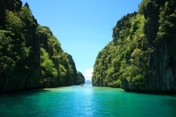 green islands with blue water stands in el nido