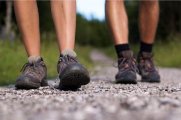 two pair of walking legs in a road with hiking boots